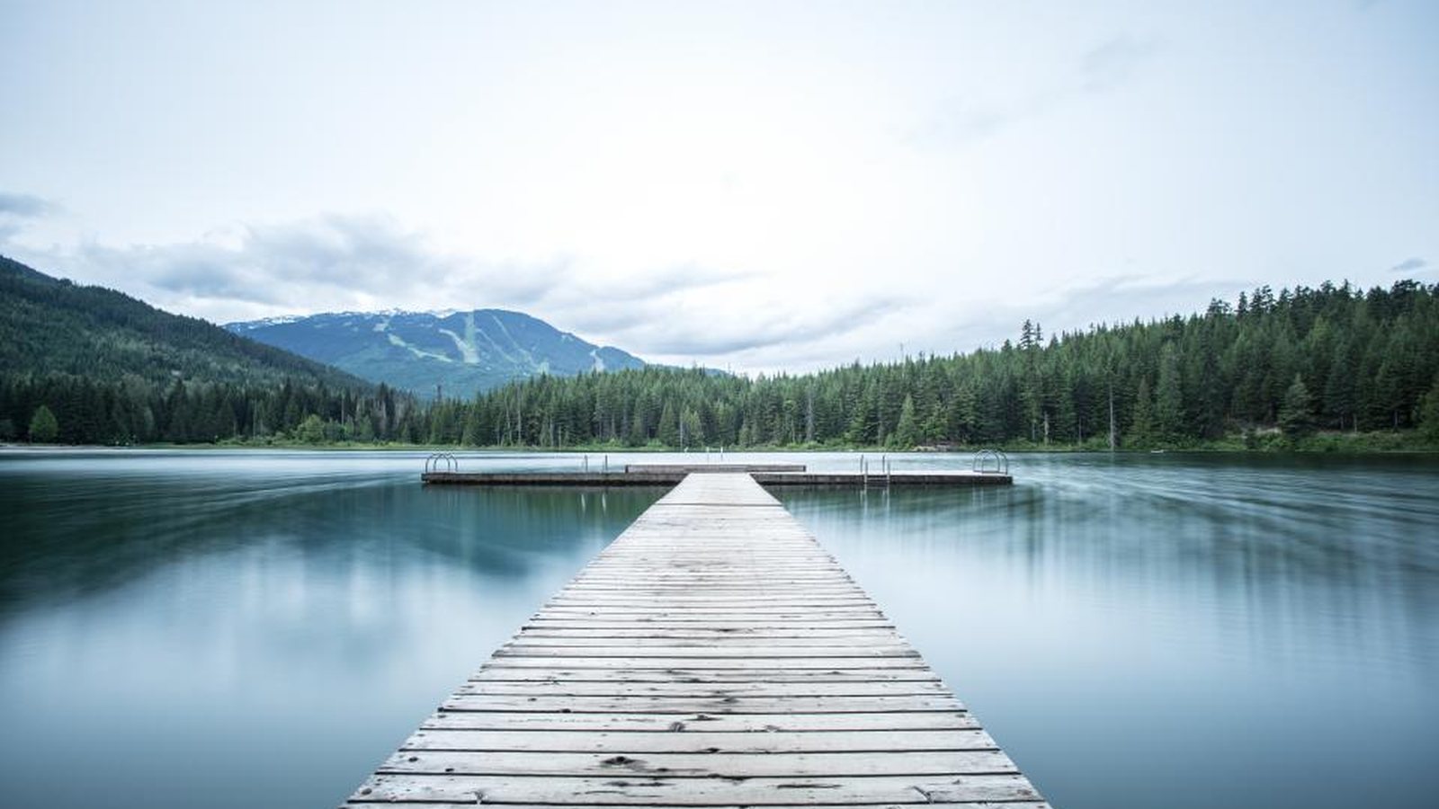 Wooden dock on a forested lake, like the shoreline properties of Lake Stevens, Washington